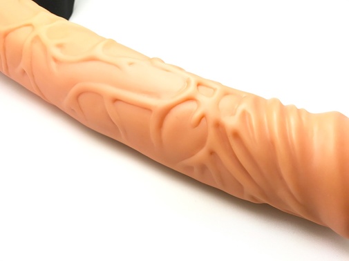 Detail na výraznou žilnatost dutého strap-on dilda v tělové barvě.