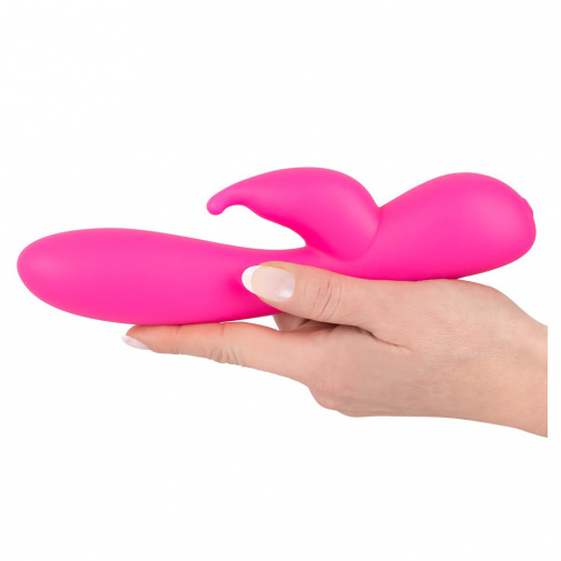Růžový silikonový vibrátor se stimulátorem klitorisu Sweet Smile Rabbit v ruce.